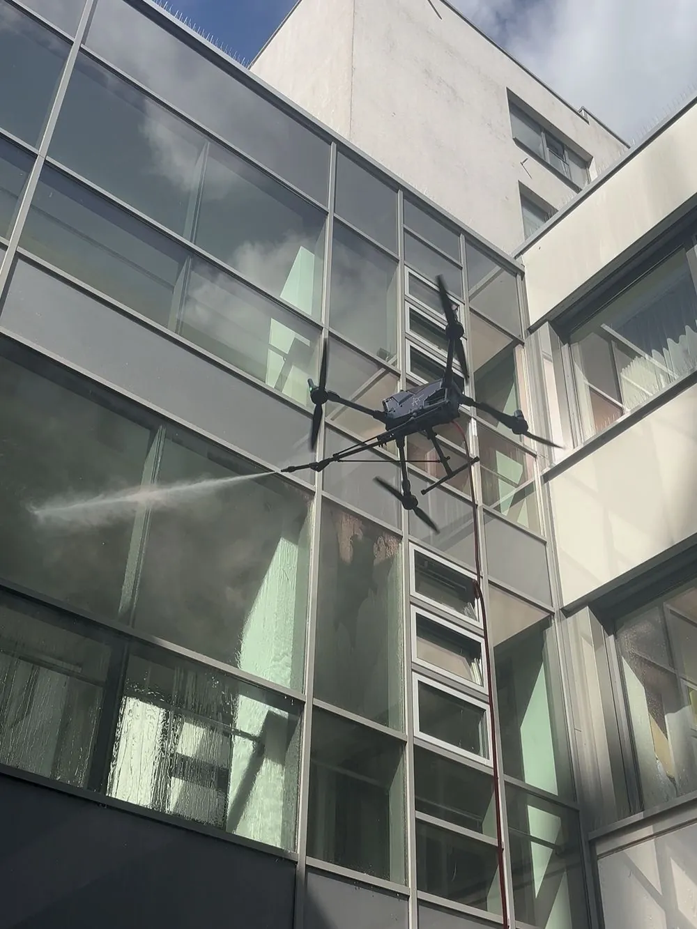 Reinigungsdrohne von APRIORI vor einer Glasfassade